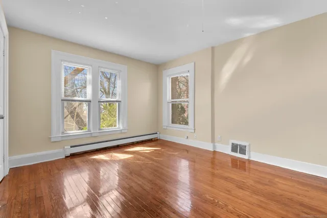 a view of an empty room with wooden floor and a window