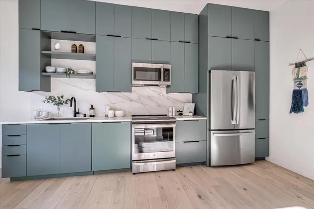a kitchen with granite countertop a refrigerator and a stove top oven