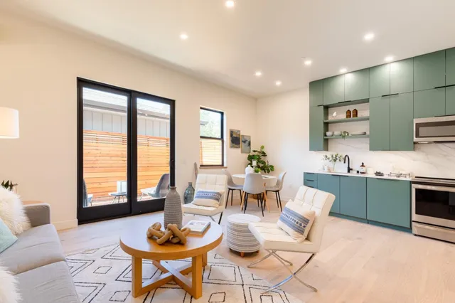 a living room with stainless steel appliances kitchen island granite countertop furniture and a large window