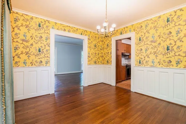 an empty room with wooden floor chandelier and windows