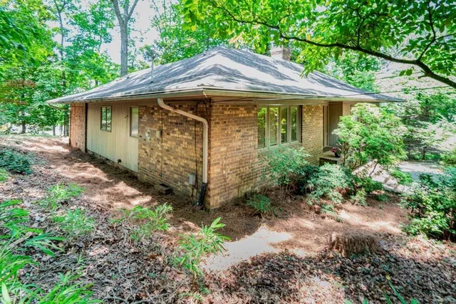 a view of a barn with a yard plants and large trees