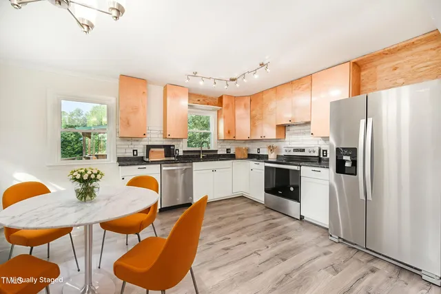 a kitchen with stainless steel appliances a stove a sink dining table and chairs