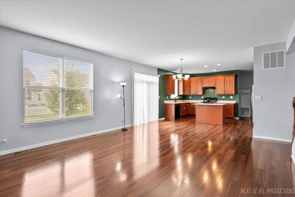 a view of a kitchen with kitchen island wooden floors stainless steel appliances and windows