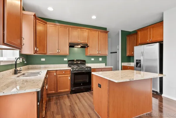 a kitchen with stainless steel appliances granite countertop a sink stove refrigerator and cabinets