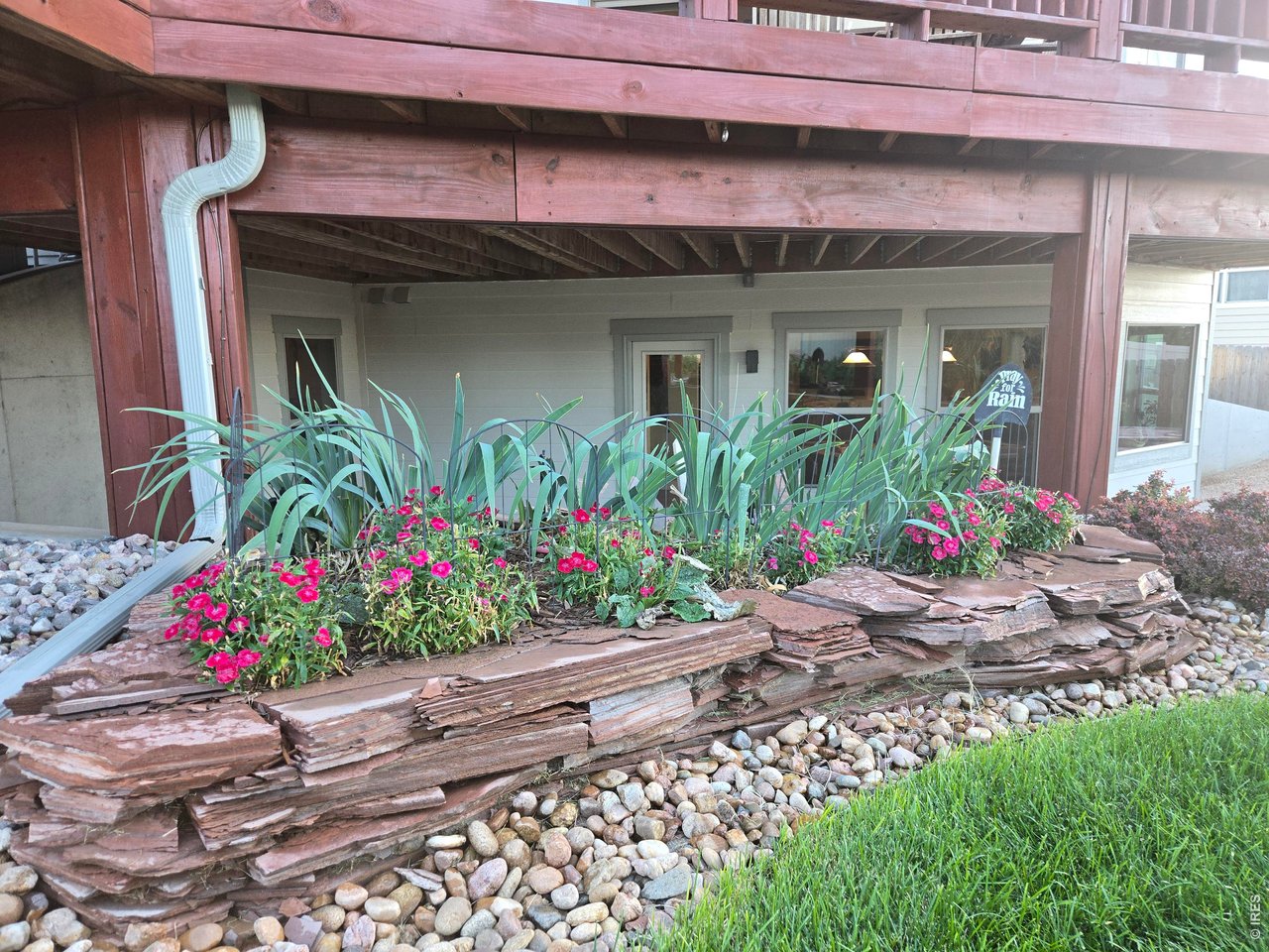 6201 West 13th St Road Greeley, CO 80634 - Photo 7 of 50 Retaining wall lies as a compliment to deck above. Lush low-maintenance landscape is the best.