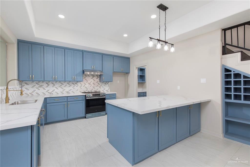 2216 South 45th Street McAllen, TX 78503 - Photo 11 of 40 a kitchen with kitchen island granite countertop a stove a sink a refrigerator and cabinets