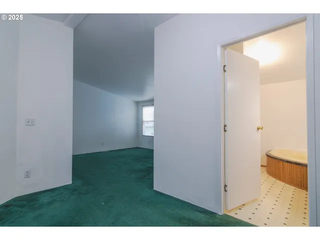 a view of an empty room with wooden floor and a bathroom