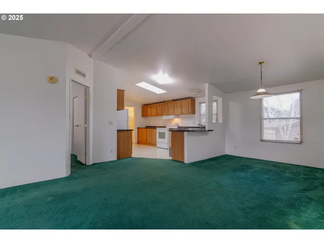 a view of kitchen with refrigerator and white cabinets