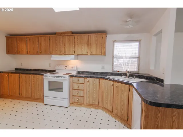 a kitchen with granite countertop a sink stove and cabinets