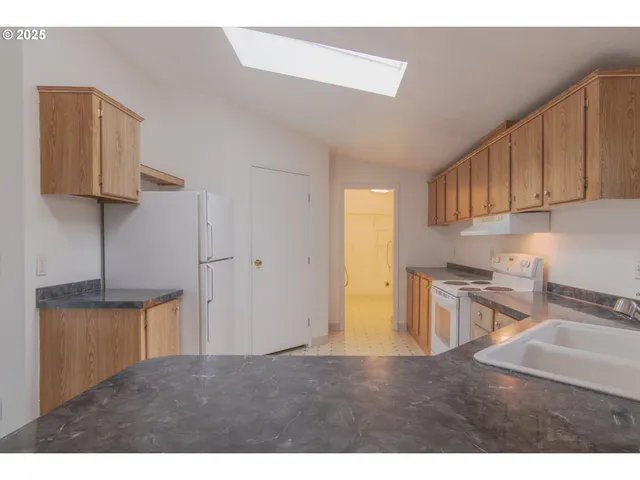 a kitchen with stainless steel appliances granite countertop a stove a sink and a refrigerator with wooden cabinets