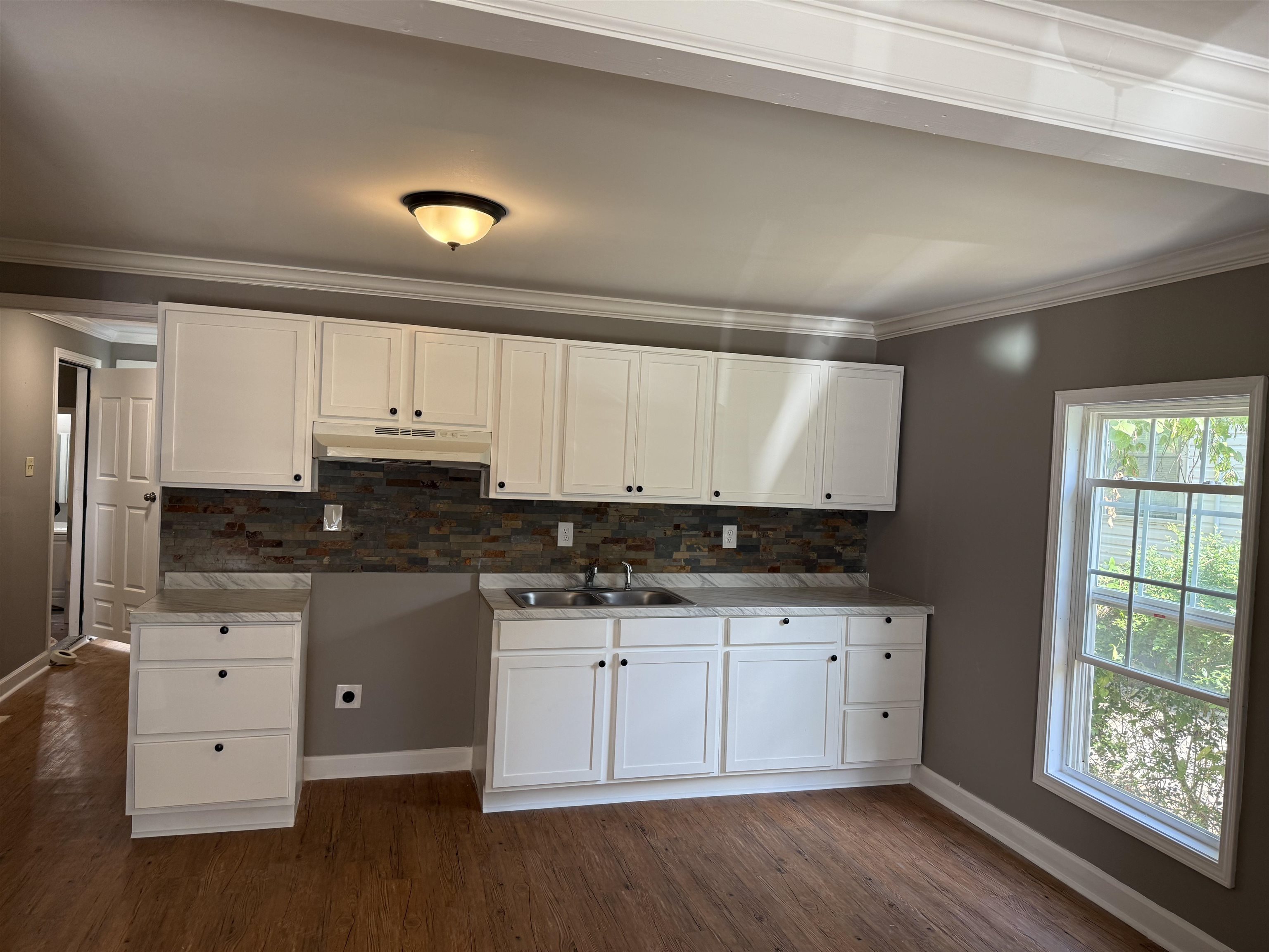 304 Harrell Street Memphis, TN 38112 - Photo 2 of 10 a kitchen with granite countertop a stove a sink and white cabinets with wooden floor