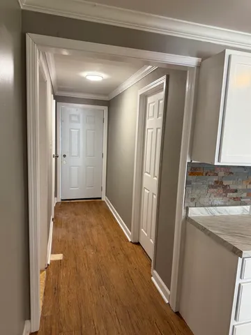 a view of a hallway with wooden floor and cabinets