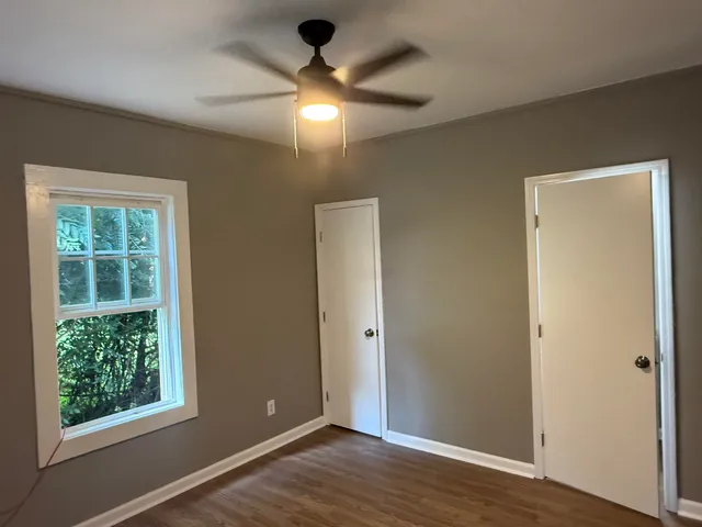 an empty room with wooden floor and windows