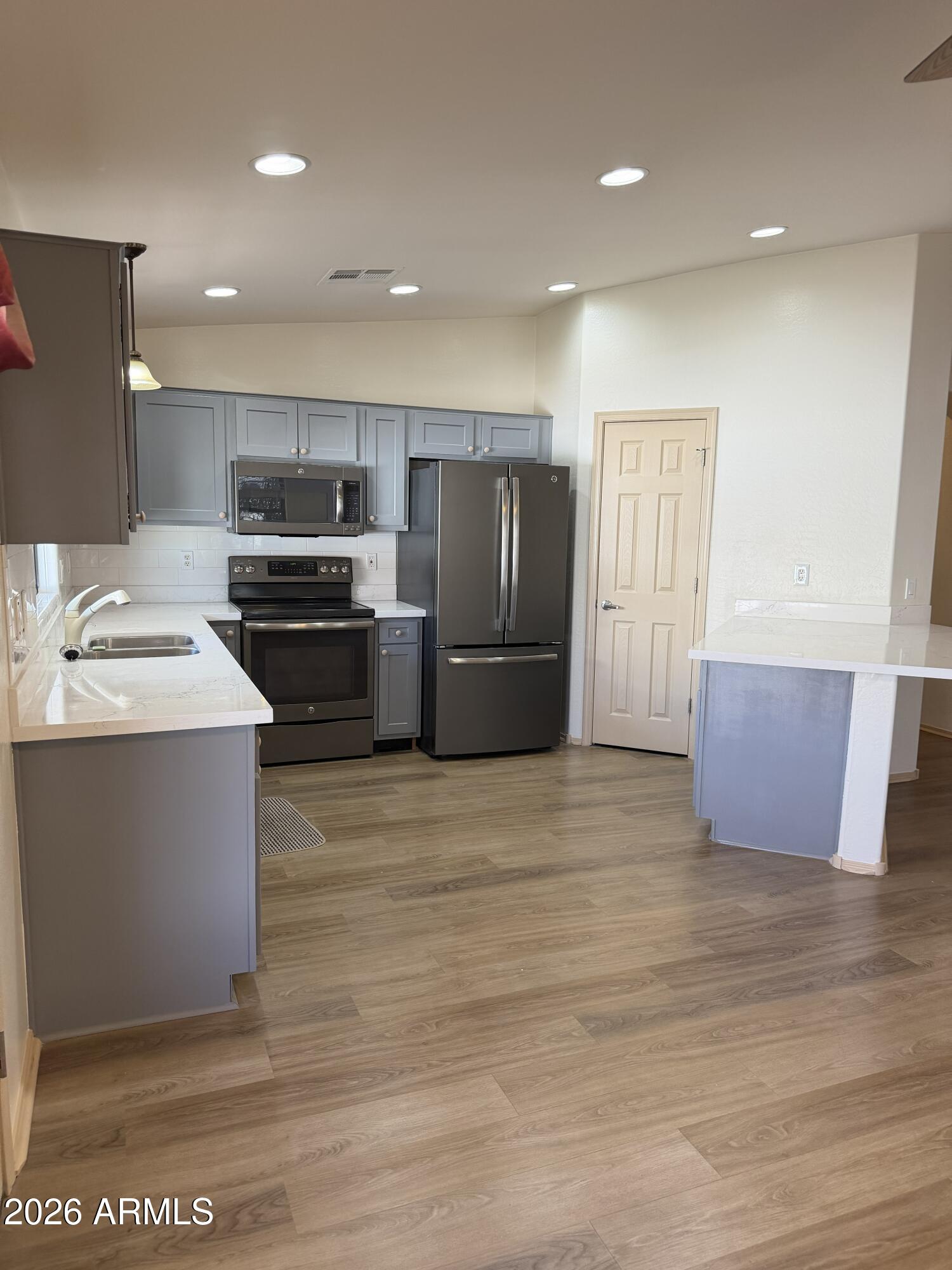2101 South Meridian Road, Unit 255 Apache Junction, AZ 85120 - Photo 6 of 24 a kitchen with stainless steel appliances a stove a sink a refrigerator white cabinets and wooden floor