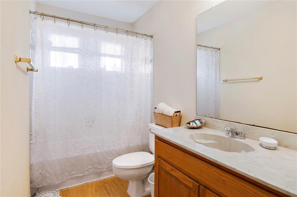 9201 Simmons Road, Unit 117 Austin, TX 78759 - Photo 8 of 11 Full bathroom featuring a single vanity with wood cabinetry and a light-toned countertop, a large wall-mounted mirror, a toilet, and a combined tub and shower area