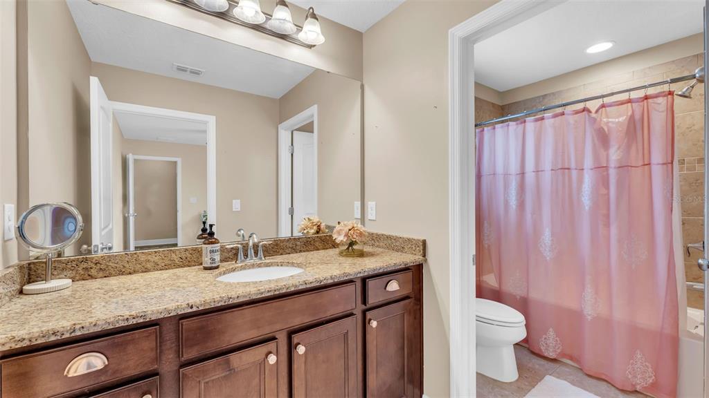 132 Magneta Loop Auburndale, FL 33823 - Photo 35 of 56 a bathroom with a granite countertop sink a toilet and a mirror
