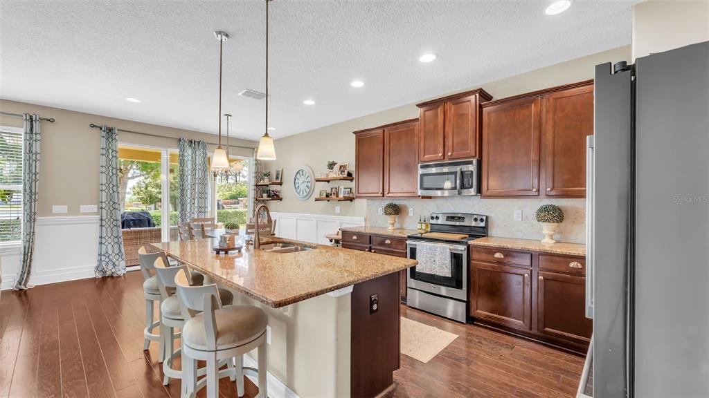 132 Magneta Loop Auburndale, FL 33823 - Photo 10 of 56 a kitchen with stainless steel appliances granite countertop a stove top oven a sink dishwasher a dining table and chairs with wooden floor