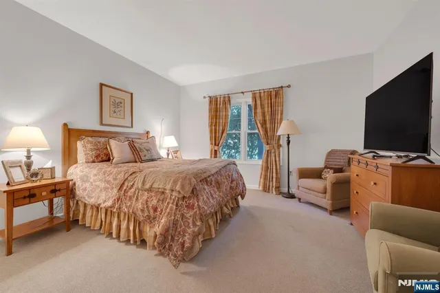 a spacious bedroom with a bed and a flat screen television