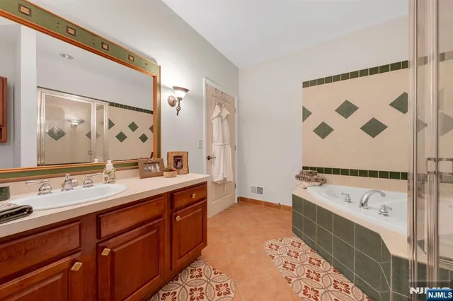 a spacious bathroom with a tub sink and mirror