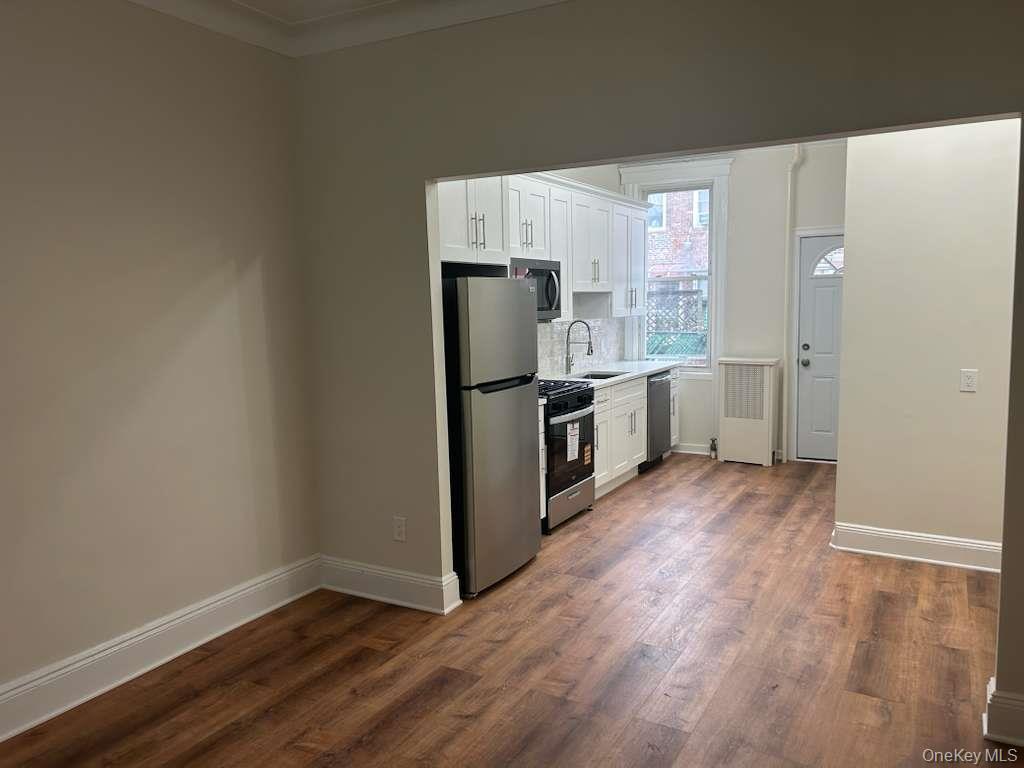 88-23 85th Street, Unit 1L Queens, NY 11421 - Photo 3 of 17 a kitchen with stainless steel appliances a refrigerator and wooden floor