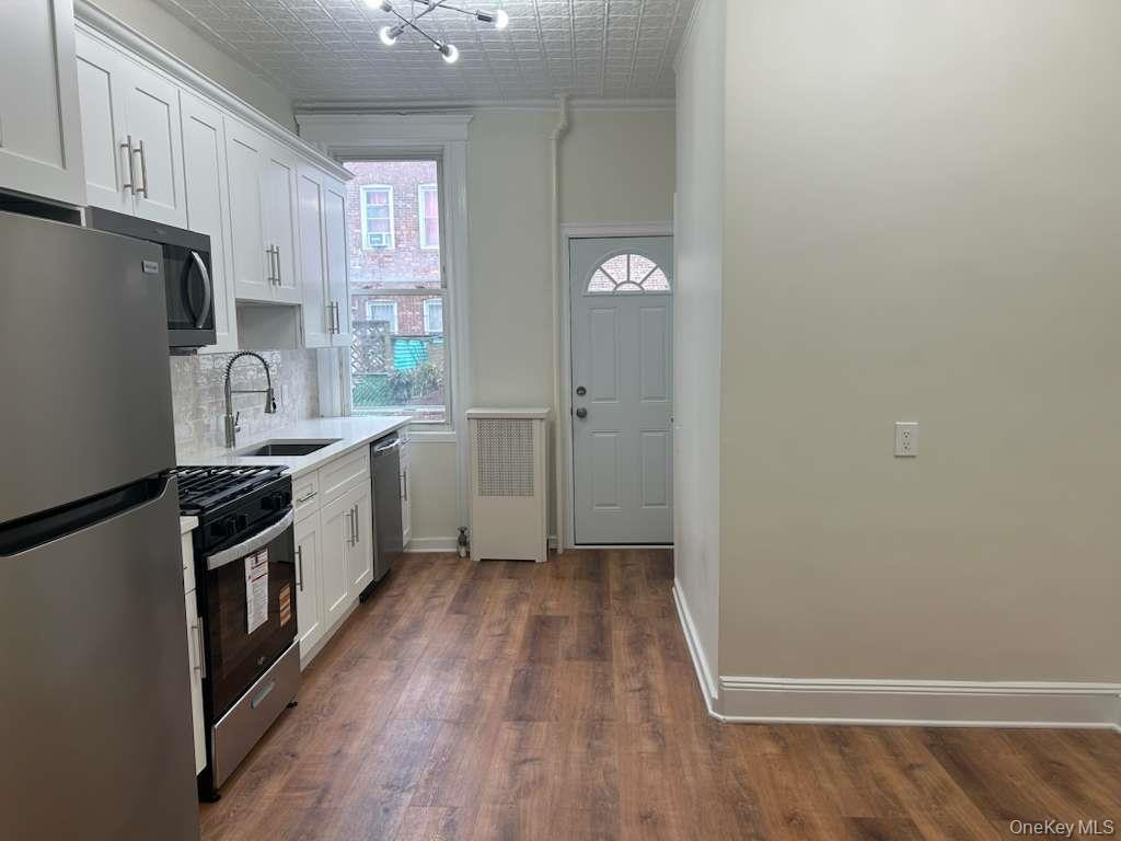 88-23 85th Street, Unit 1L Queens, NY 11421 - Photo 4 of 17 a kitchen with a sink a stove a refrigerator and cabinets