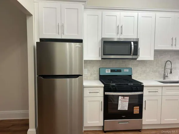 a kitchen with stainless steel appliances white cabinets white stove and a refrigerator with wooden floor
