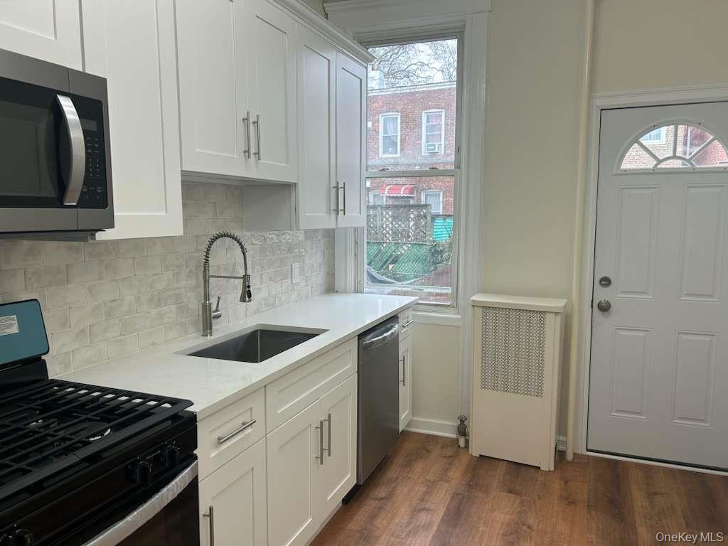 88-23 85th Street, Unit 1L Queens, NY 11421 - Photo 6 of 17 a kitchen with stainless steel appliances granite countertop a sink stove and cabinets