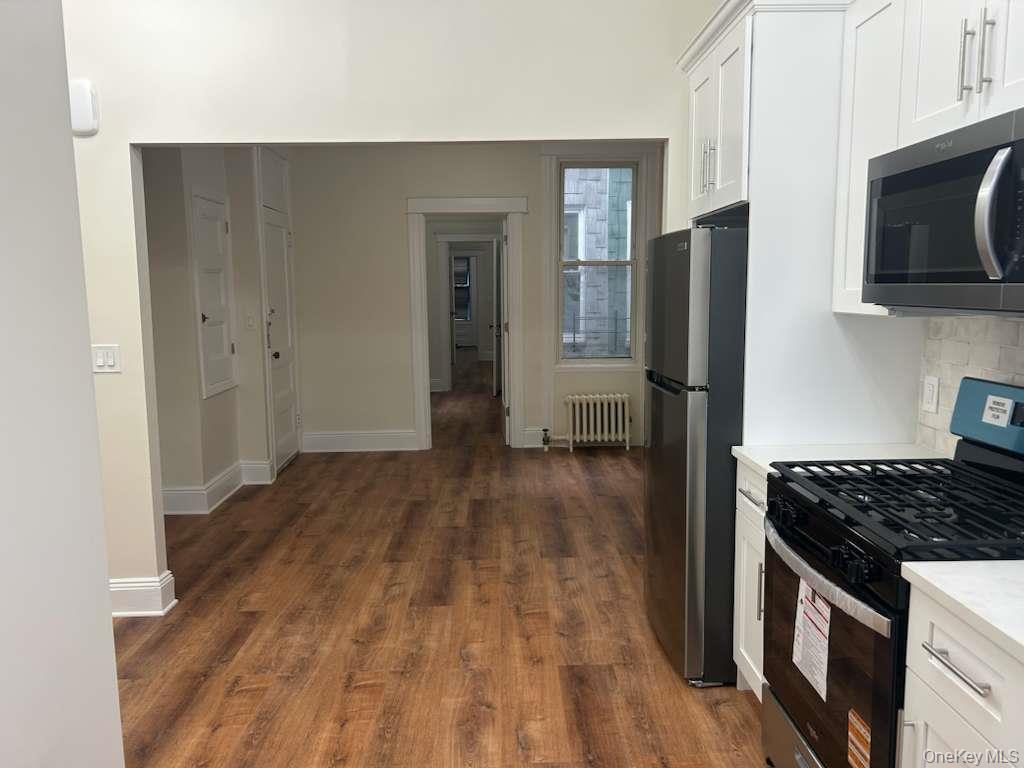 88-23 85th Street, Unit 1L Queens, NY 11421 - Photo 7 of 17 a kitchen with wooden floors and appliances