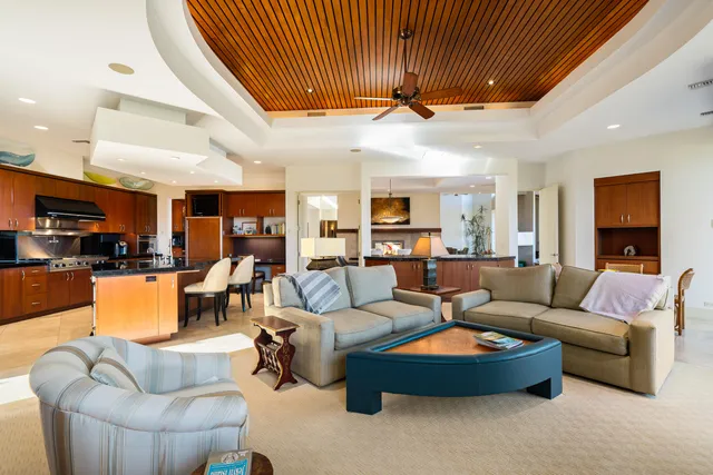 a living room with furniture kitchen view and a chandelier