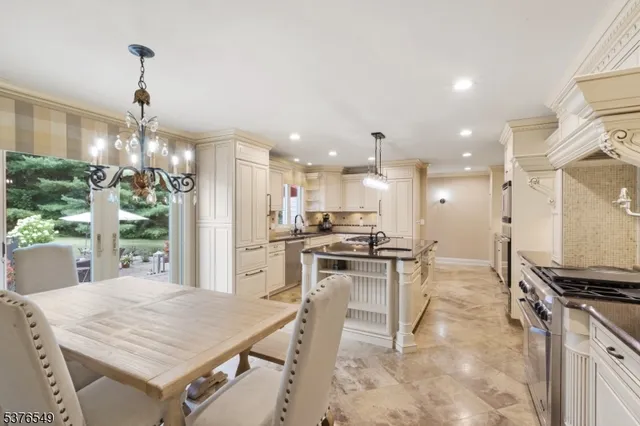 a kitchen with stainless steel appliances kitchen island granite countertop a stove a refrigerator a oven a sink with a dining table and chairs