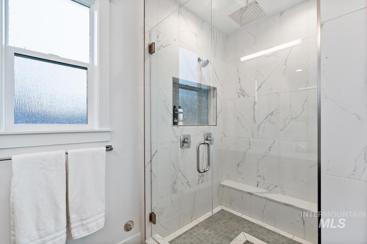 599 West Warren Street Boise, ID 83706 - Photo 22 of 41 Shower enclosure featuring clear glass panels, marble-look tile walls, a built-in bench, and a square rain showerhead