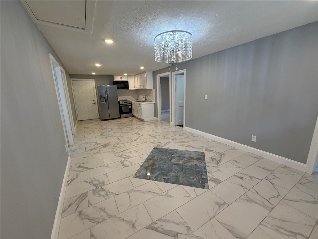 302 Sirrine Street Honea Path, SC 29654 - Photo 6 of 24 An open-concept living space features an elegant chandelier and marble-inspired tile flooring.