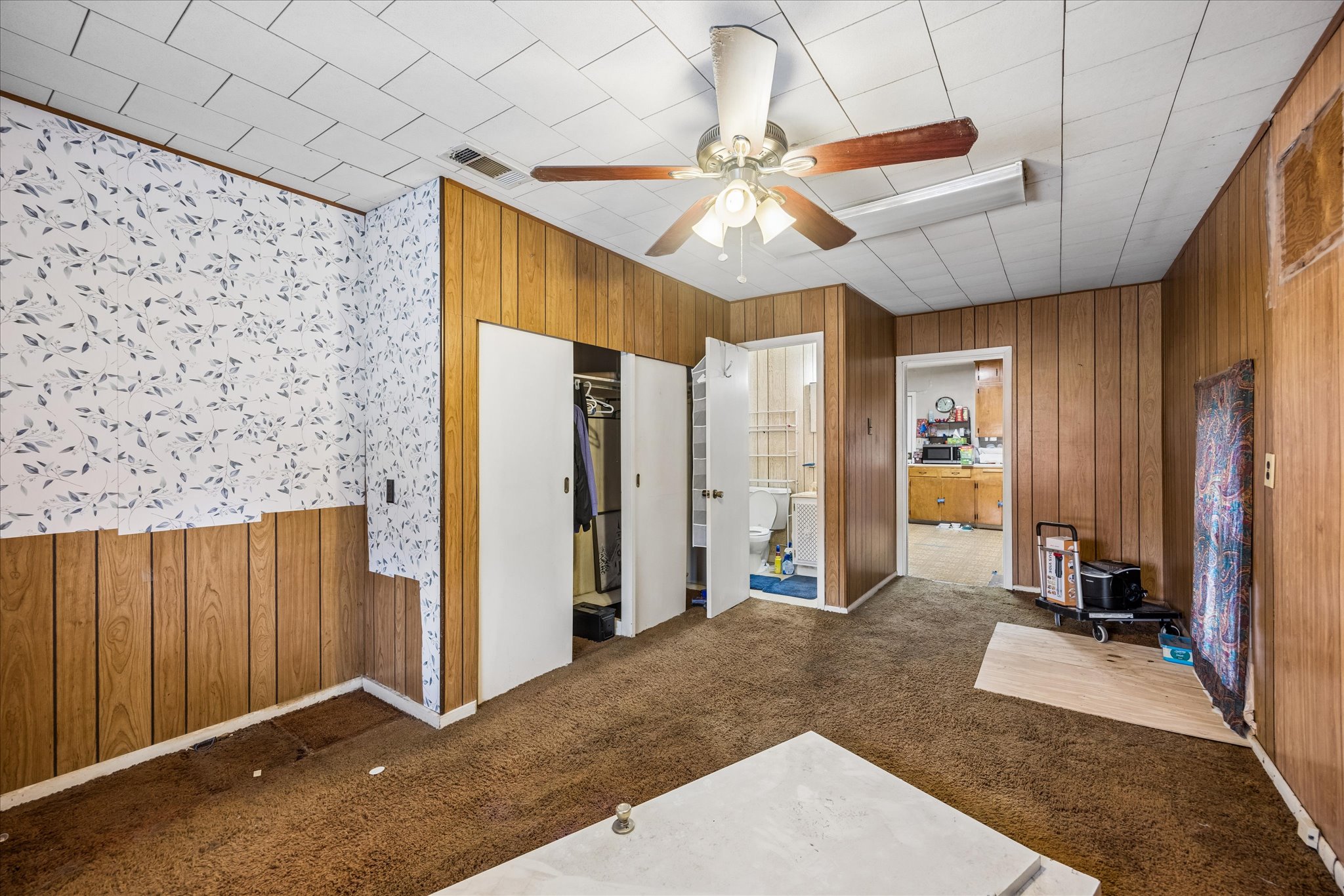 2009 Fort View Road Austin, TX 78704 - Photo 25 of 40 A utilitarian room features a ceiling fan, plush carpet, and paneling, with an adjoining bathroom and kitchen visible.
