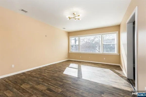 a view of an empty room with a window and wooden floor