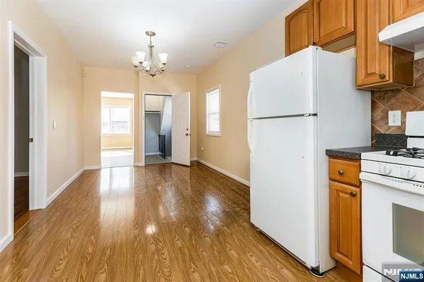 a view of a hallway with wooden floor and a refrigerator