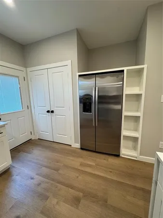 a view of an empty room with wooden floor and closet