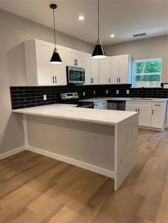 a large kitchen with stainless steel appliances a large counter top a stove a chimney a sink and a large window
