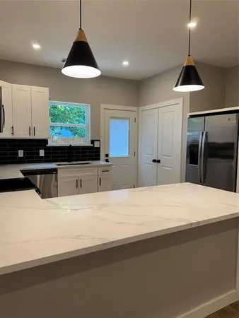 a kitchen with stainless steel appliances a stove a refrigerator a sink and a large window