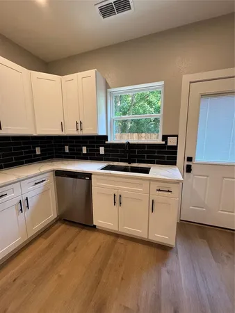 a kitchen with granite countertop white cabinets and white appliances with wooden floor
