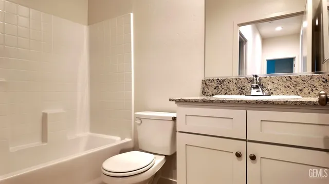 a bathroom with a granite countertop toilet sink and mirror