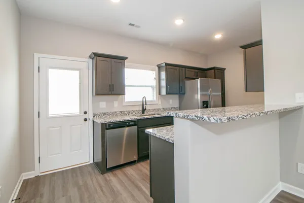 a kitchen with stainless steel appliances granite countertop a refrigerator and a stove top oven
