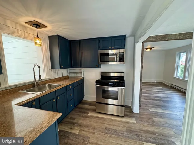 a kitchen with stainless steel appliances kitchen island granite countertop a sink and wooden cabinets