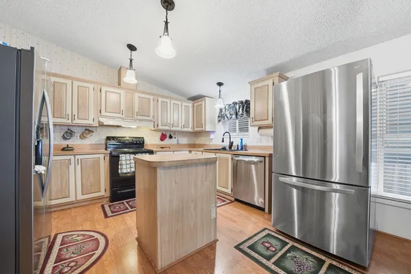 a kitchen with stainless steel appliances granite countertop a refrigerator a stove a sink and a refrigerator