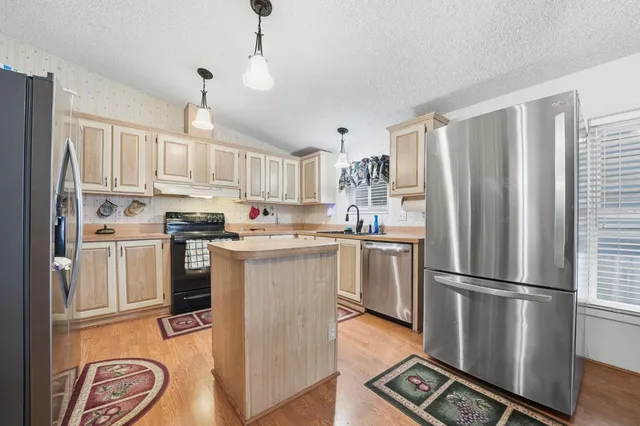 a kitchen with stainless steel appliances granite countertop a refrigerator a stove a sink and a refrigerator