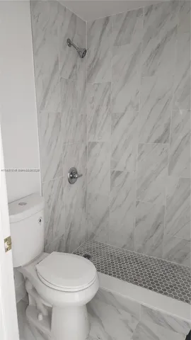 a white toilet sitting next to a shower