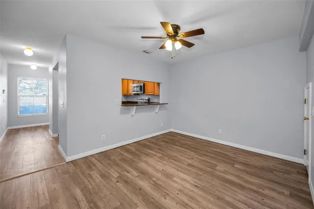 a view of empty room with wooden floor and fan