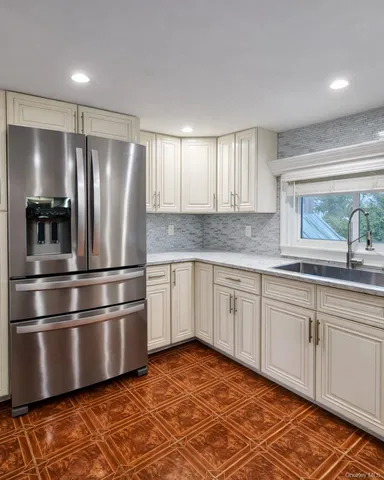 a kitchen with stainless steel appliances granite countertop a refrigerator a sink and white cabinets