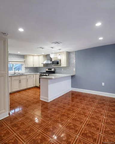 a large kitchen with kitchen island granite countertop a stove a sink a counter space and cabinets