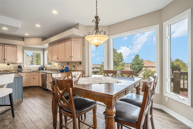 a view of a kitchen with kitchen island stainless steel appliances wooden floor dining table and chairs