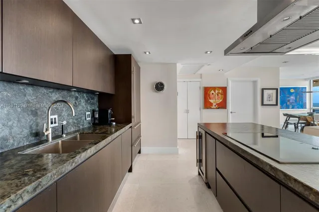 a kitchen with granite countertop stainless steel appliances a sink a counter top space and cabinets